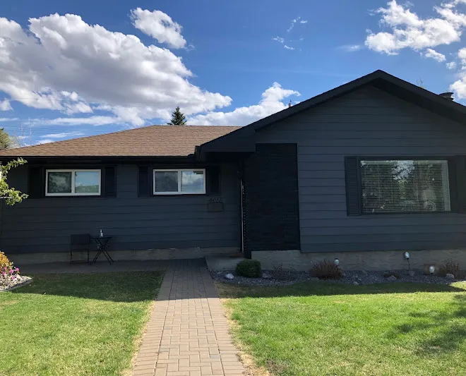 Bungalow exterior repainted in deep navy with crisp white trim — Leonard’s Painting, Edmonton area