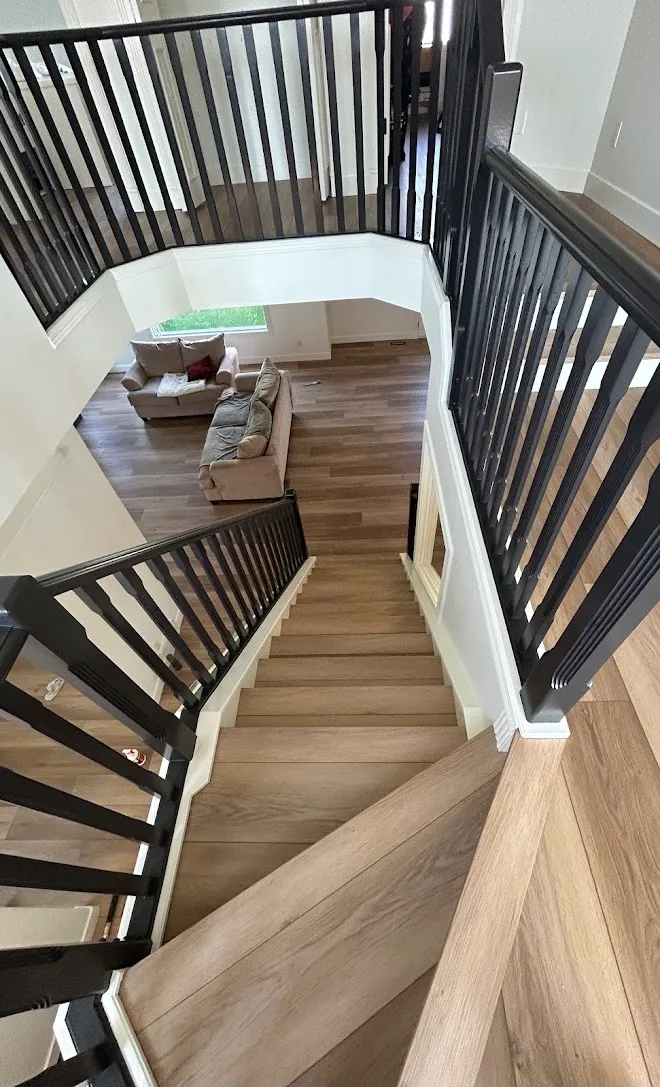 Curved staircase with railings repainted black over new hardwood — Leonard’s Painting, Edmonton area