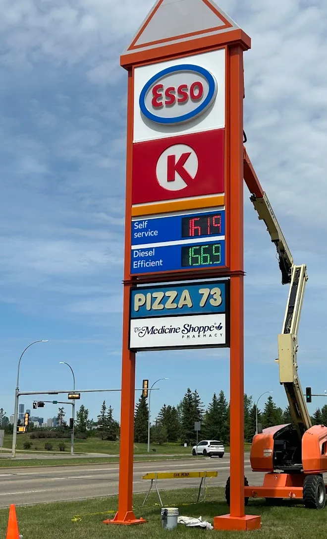 Tall gas station highway sign being repainted from a boom lift — Leonard’s Painting, Edmonton area