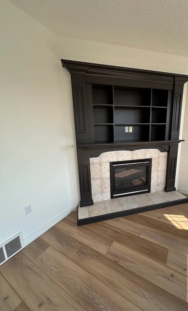 Espresso-finished built-in shelving around a tiled fireplace — Leonard’s Painting, Edmonton area