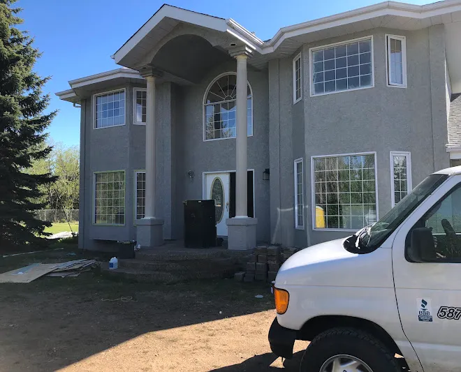 Leonard’s Painting work van parked outside a two-storey stucco repaint