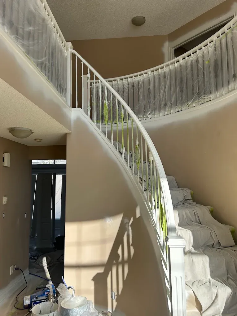 Curving white staircase with fresh paint on risers and spindles — Leonard’s Painting, Edmonton area