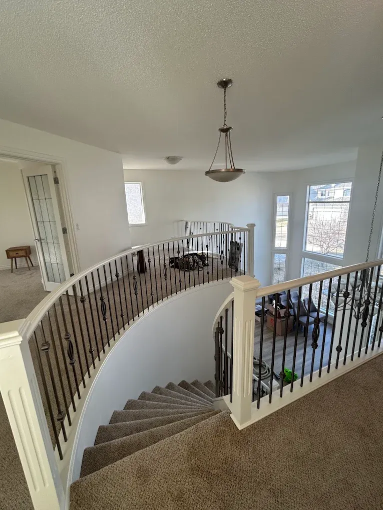Circular upper landing with repainted white and iron railings — Leonard’s Painting, Edmonton area